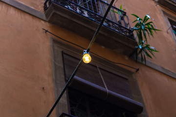 Obraz premium Decorative light bulb hanging on the string with the window on the background - Image