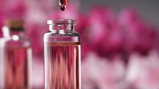 Blend of essential oils. Making some aroma liquids, perfume. Drops falling from pippet to little glass bottle. Slowmotion.