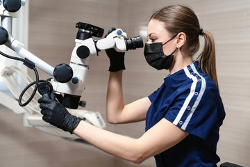 Doctor making teeth examination research survey using microscope in dentistry. Dentist is treating patient in modern dental office.