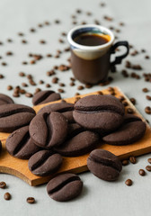 ginger biscuits with cocoa in the form of coffee beans on a wooden board on a gray background
