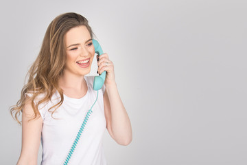beautiful girl, young adult, smiling and screaming over the phone, holding blue land line phone Telephone Headset, horizontal isolated on white, blond model