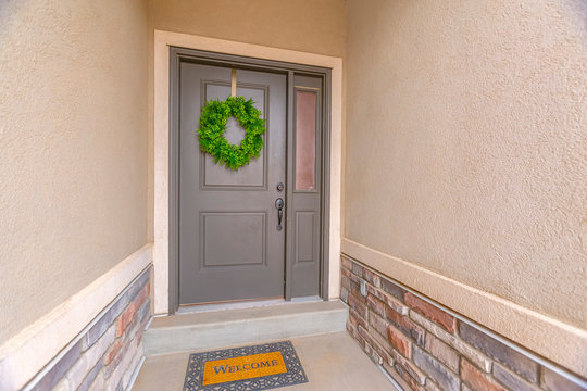 Gray Front Door Of A Home With A Simple Green Wreath And Sidelight