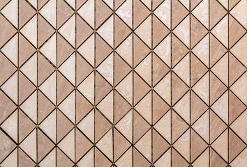Beige tiles wall or floor with light floral decoration. Repeating graphic design, flat surface, geometrical background.