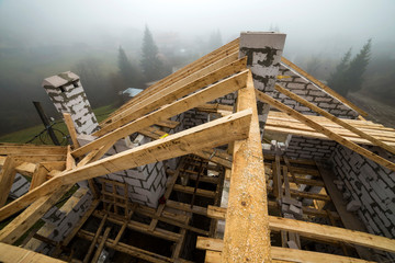 Top view of roof frame from wooden lumber beams and planks on walls made of hollow foam insulation blocks. Building, roofing, construction and renovation concept.