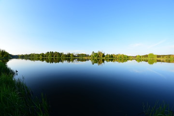 Błękitne niebo o zachodzie słońca nad spokojną wodą.