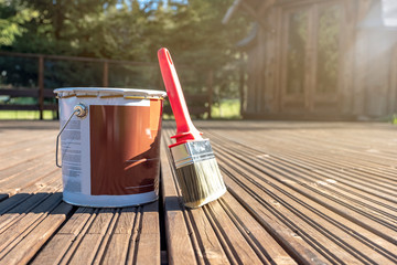On the painted boards of the terrace there is a can of paint and a large brush. Summer day, the sun...