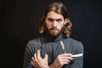 Portrait of hairdresser at black background isolated. Portrait of bearded man. Barber with scissors...