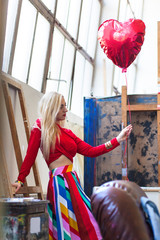 woman holding red balloon in shape of a heart