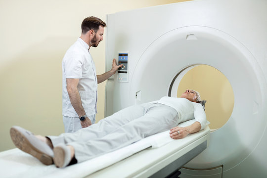 Radiologist and patient during MRI scan procedure in medical examination room.