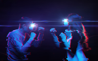 Couple with virtual reality headset are playing game and fighting. Man vs woman. Image with glitch effect.