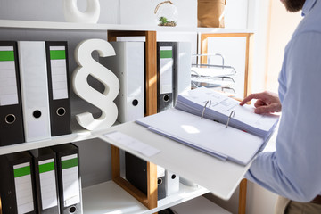 Businessperson Taking Folder From Shelf