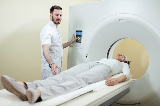 Radiologist preparing a patient for an MR scan examination at clinic.