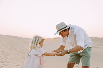 Happy father playing with his little daughter in the desert