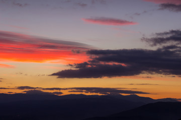 Fototapeta na wymiar Amazing vivid colors of a sunset sky and clouds and distant horizon mountains