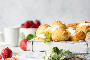 Profiteroles (choux à la crème) - French choux pastry balls filled with cottage cheese and cream with fresh strawberry, mint and cup of coffee.