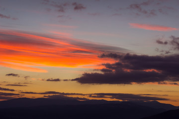 Obraz premium Amazing vivid colors of a sunset sky and clouds and distant horizon mountains