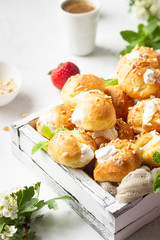 Profiteroles (choux à la crème) - French choux pastry balls filled with cottage cheese and cream with fresh strawberry, mint and cup of coffee.
