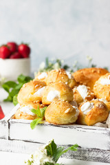 Profiteroles (choux à la crème) - French choux pastry balls filled with cottage cheese and cream with fresh strawberry, mint and cup of coffee.