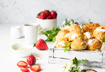 Profiteroles (choux à la crème) - French choux pastry balls filled with cottage cheese and cream with fresh strawberry, mint and cup of coffee.