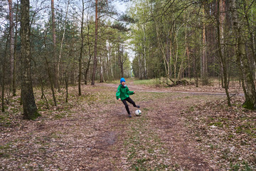 chłopak gra w piłkę w lesie