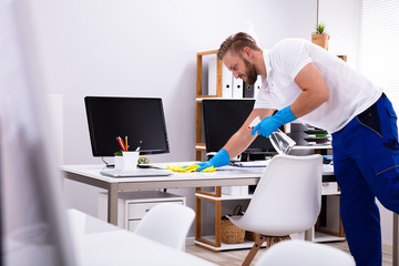 Janitor cleaning white desk in office