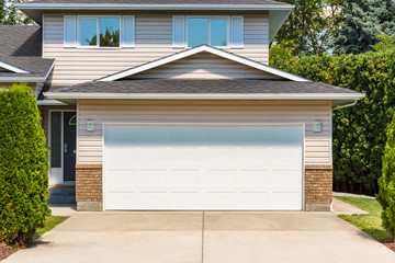 Wide garage door of residential house with concrete driveway in front - obrazy, fototapety, plakaty