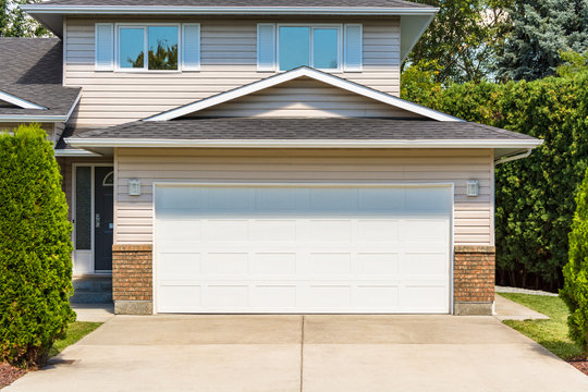 Wide garage door of residential house with concrete driveway in front