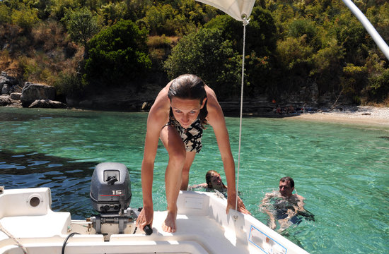 Girl getting into a boat after swim in the sea