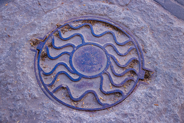 the round cover of the drain well that is on the road