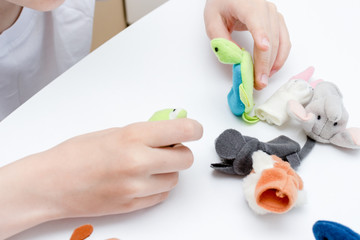 A caucasian boy playing finger puppets, toys, dolls - figures of animals, heroes of the puppet theatre put on fingers of human hand