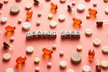 Black and white title HEALTH CARE from white cubes on the table with tablets on coral background