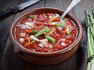 clay casserole with tomato sauce and cut vegetables, in rustic wood