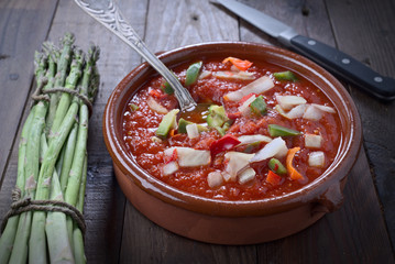 clay casserole with tomato sauce and cut vegetables, in rustic wood