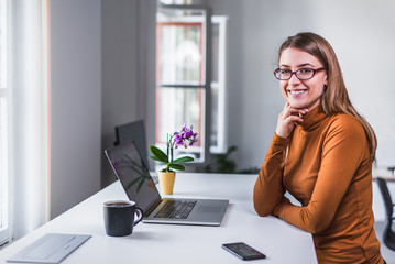 Businesswoman with glasses who loves her job smiles at camera