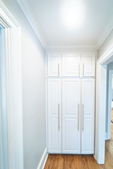 Wall of Tall White wood Painted Cabinets with modern gold handles hardware for storage