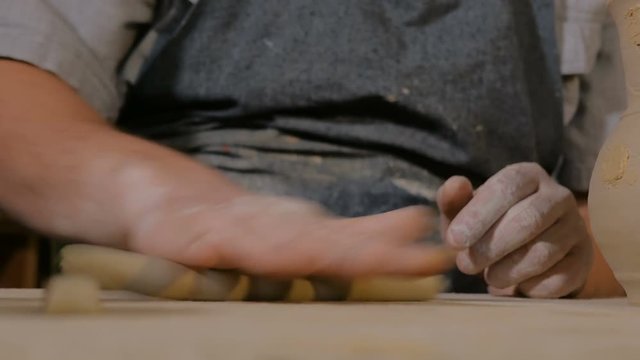 Professional male potter working in workshop, studio - making handle of ceramic mug. Handmade, small business, crafting work concept