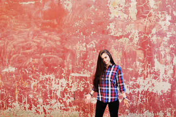 portrait of cute young brunette girl in plaid shirt on red grunge wall background.