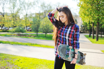 cute girl with skateboard on the background of the Park