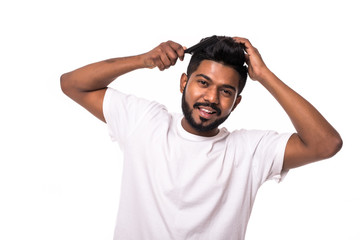 Fototapeta na wymiar Portrait of happy smiling handsome indian man combing his hair on white background