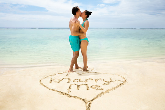 Marry Me Text In Front Of Couple On Beach