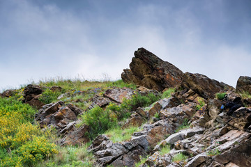 Fototapeta na wymiar Stone cavern in green steppe landscape view with cloudy sky