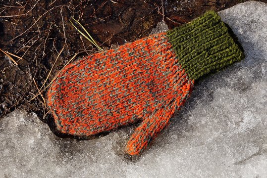 One Colored Wool Mitten Lies On White Snow And Earth