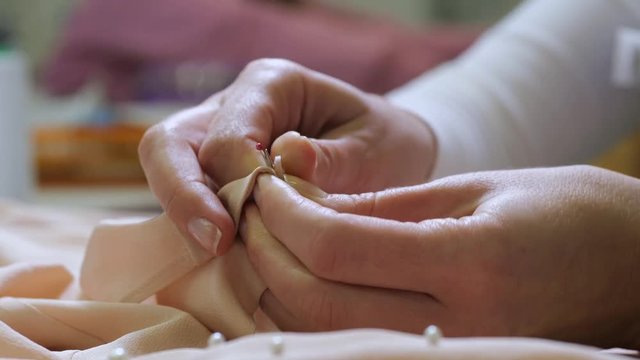 Close-up of woman employee's hands stripping buttons off blouse to avoid their damage during process of professional dry-cleaning. Female worker preparing exclusive clothes for dry cleaning in salon