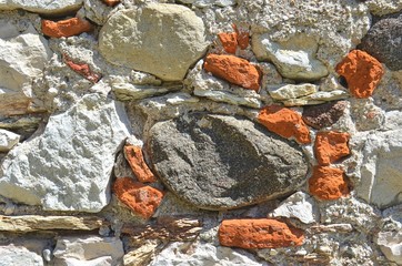 ancient stone wall made of multi-colored stones, different in shape and size