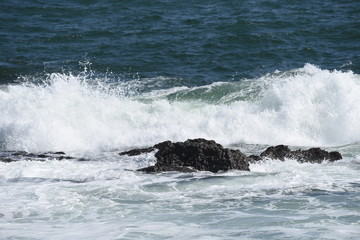The scene of the beach. Waves crashing into rocks.