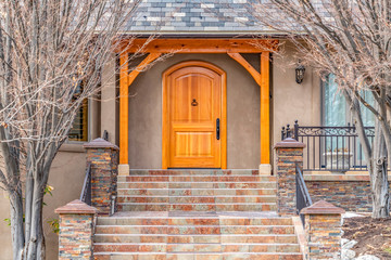 Entryway of home framed with leafless hibernating trees on the yard in winter