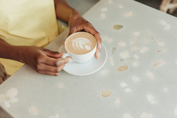 Cropped photo of African woman having rest and drinking coffee in cafeteria