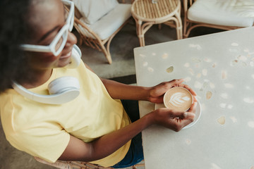 Cropped photo of African woman having rest and drinking coffee in cafeteria
