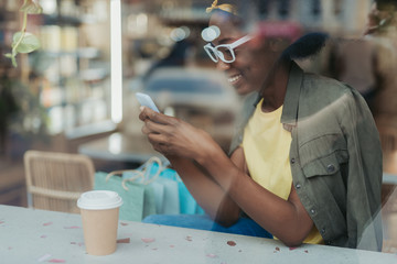 Side view of happy African lady having rest in cafeteria