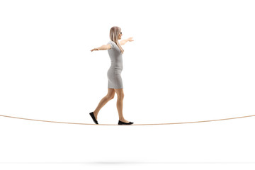Young blond woman walking on a rope with arms spread